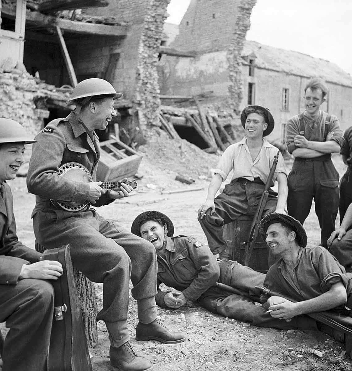 George Formby entertains troops in the ruins of a village in Normandy, France during World War II on his banjolele, 1944 Source: Wikimedia Commons